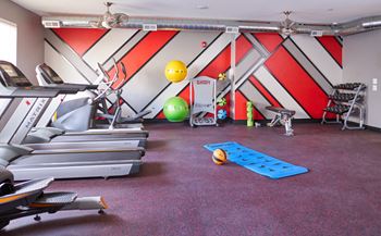 a gym with treadmills and other exercise equipment in a room with a wall at Vue Apartments, IA, 50309